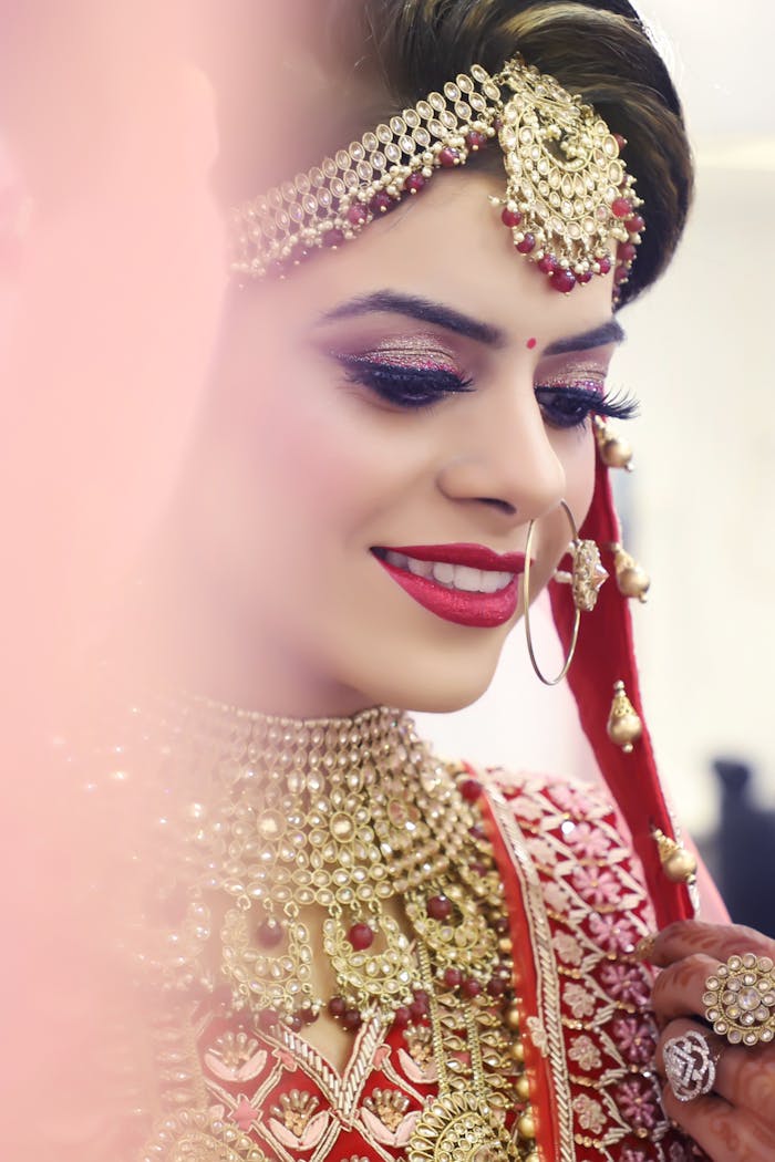 Close-up portrait of a bride adorned with gold jewelry and intricate makeup.
